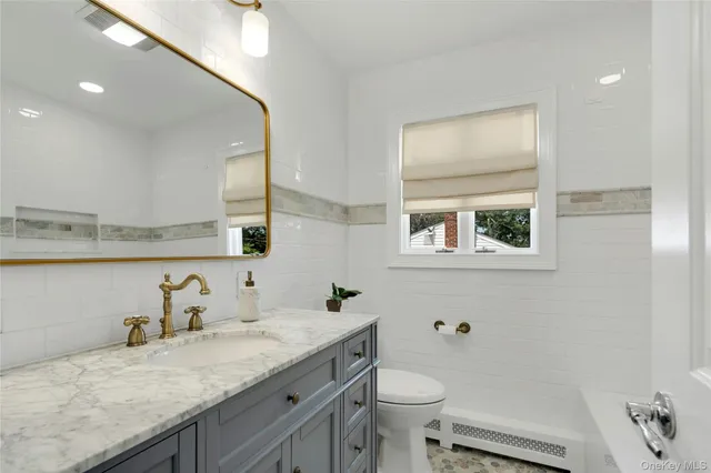 a bathroom with a granite countertop sink a toilet and a mirror