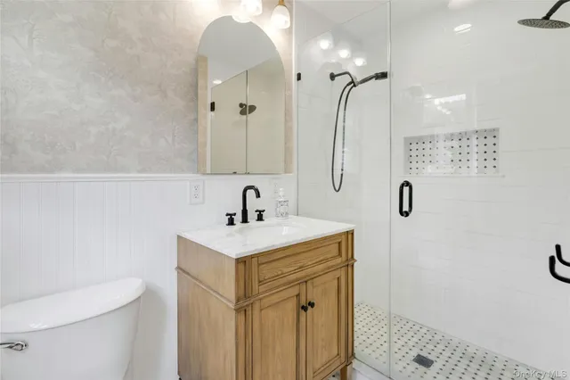 a bathroom with a sink a toilet a mirror and shower