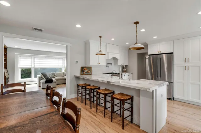 a kitchen with stainless steel appliances kitchen island granite countertop a table chairs refrigerator and sink