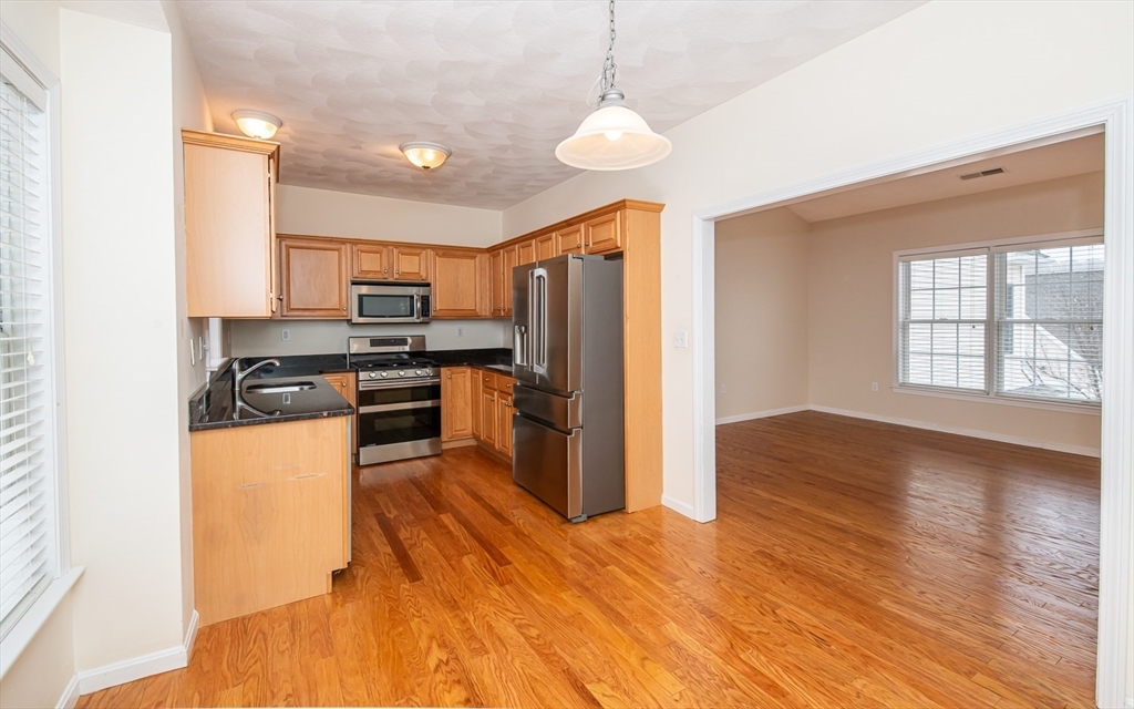 401 Autumn Ridge Drive, Unit 401 Ayer, MA 01432 - Photo 14 of 33 a kitchen with stainless steel appliances granite countertop a refrigerator a stove top oven a sink dishwasher and wooden floor
