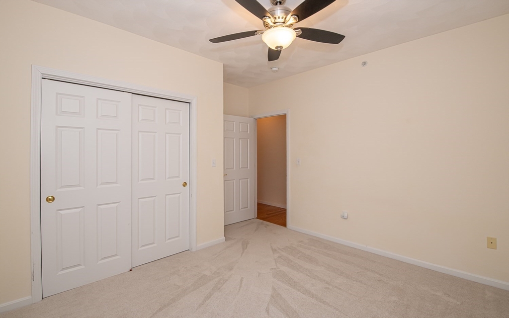 401 Autumn Ridge Drive, Unit 401 Ayer, MA 01432 - Photo 20 of 33 an empty room with closet and a chandelier fan