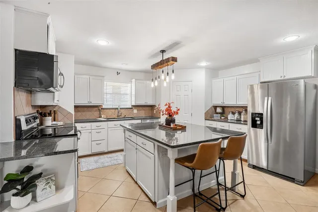 a kitchen with refrigerator a sink and chairs