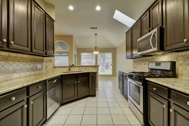a kitchen with stainless steel appliances granite countertop a stove a sink and a microwave