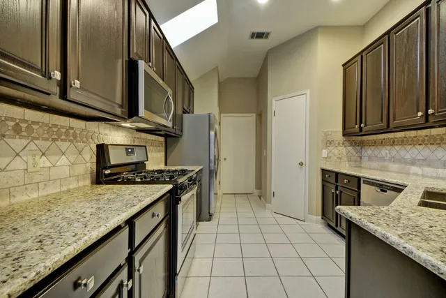 a kitchen with stainless steel appliances granite countertop a stove a sink and a microwave