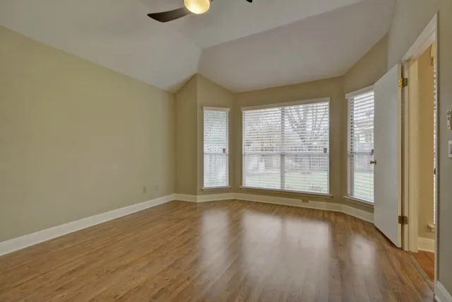a view of an empty room with wooden floor and a window