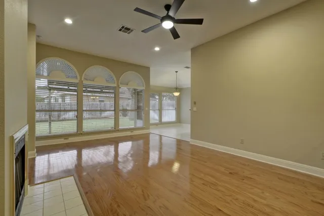 a view of empty room with wooden floor and fan