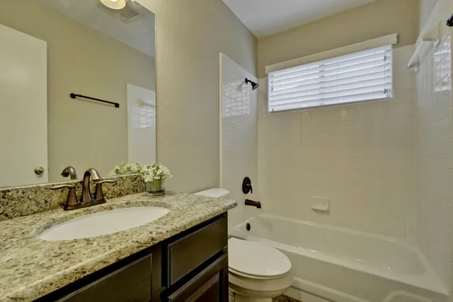a bathroom with a granite countertop sink toilet and shower