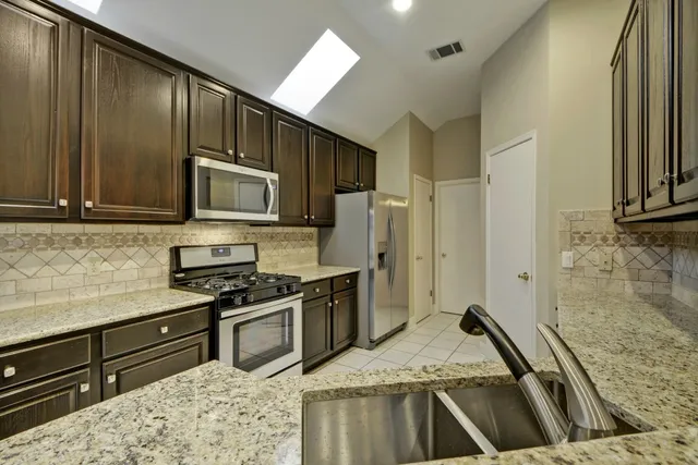 a kitchen with stainless steel appliances granite countertop a stove a sink and a microwave