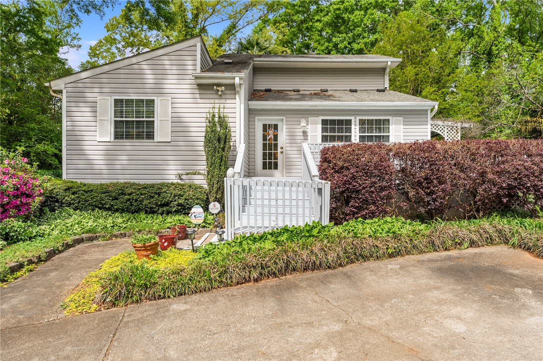 This charming residence features appealing low maintenance siding and a welcoming entrance surrounded by lush greenery.