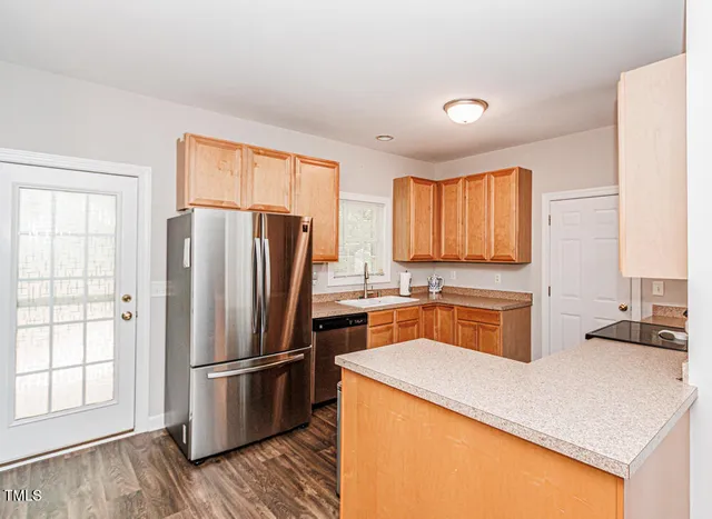 a kitchen with a refrigerator a stove a sink dishwasher and wooden cabinets with wooden floor