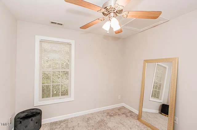 an empty room with windows and fan