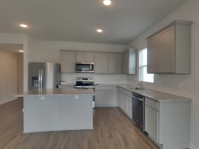 a large kitchen with stainless steel appliances a sink a stove a refrigerator cabinets and a center island