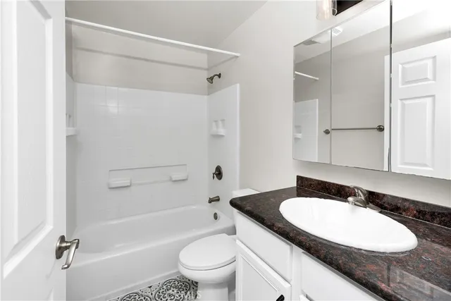 a bathroom with a granite countertop sink toilet a mirror and shower