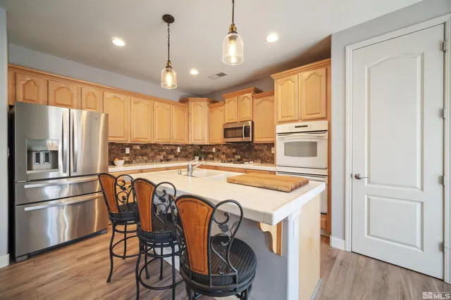 a kitchen with kitchen island granite countertop a refrigerator a stove a sink and white cabinets with wooden floor