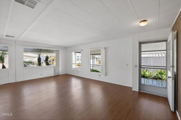 an empty room with wooden floor and windows