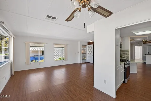 an empty room with wooden floor chandelier and windows