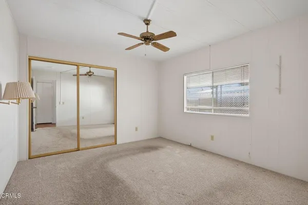 an empty room with a ceiling fan and glass door