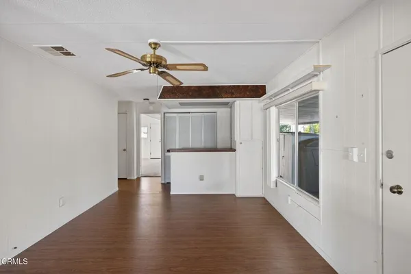 a view of a room with a ceiling fan and hardwood floor