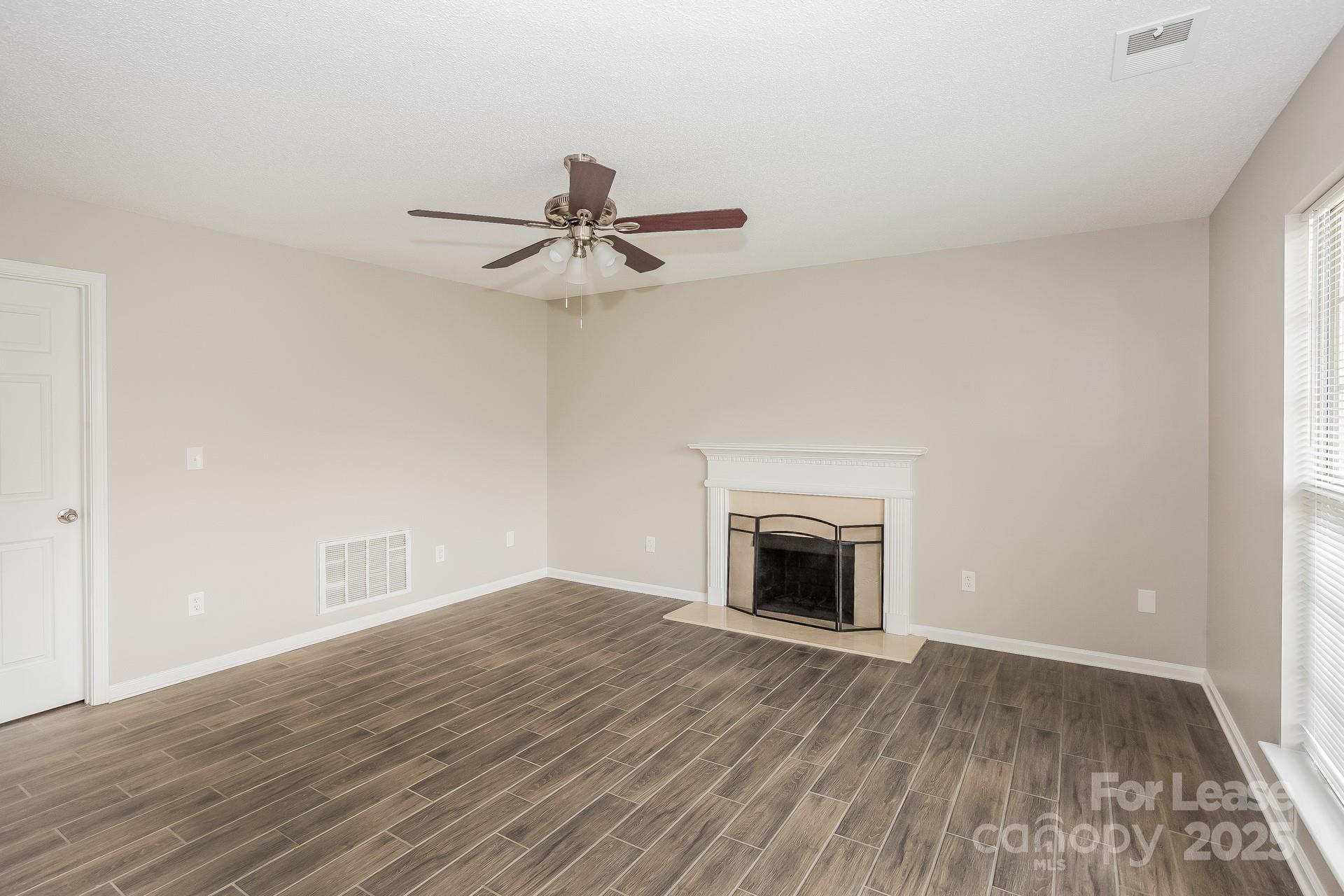 14319 Ruddy Court Charlotte, NC 28273 - Photo 3 of 16 a view of an empty room with wooden floor a fireplace and a window