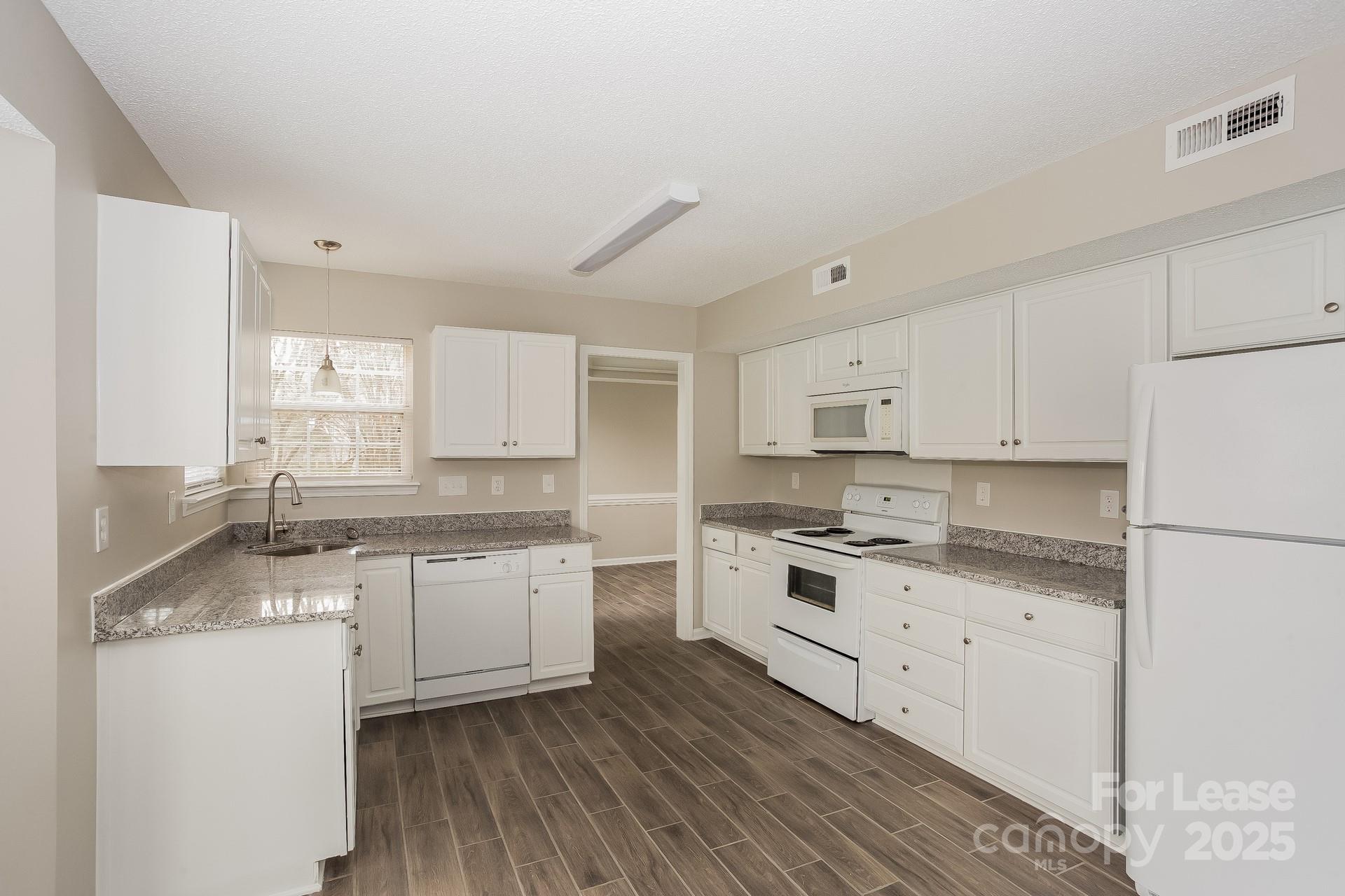 14319 Ruddy Court Charlotte, NC 28273 - Photo 5 of 16 a kitchen with granite countertop white cabinets and white appliances