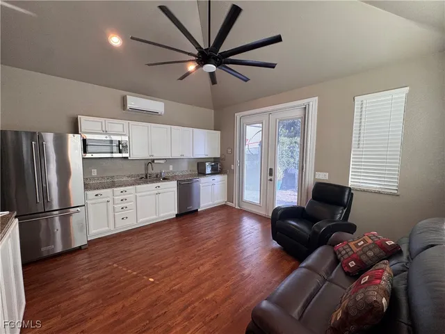 a living room with stainless steel appliances furniture and a kitchen view