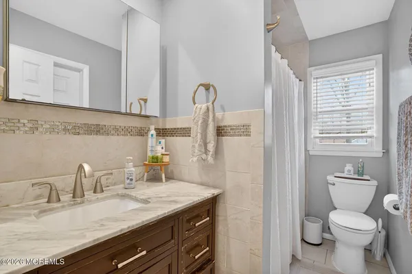 a bathroom with a granite countertop toilet sink and mirror