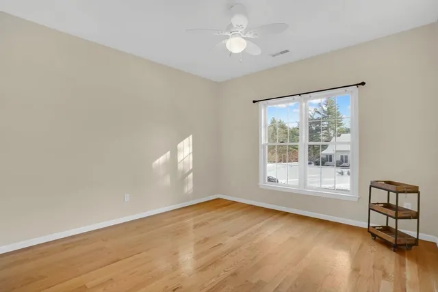 a view of an empty room with a window and wooden floor