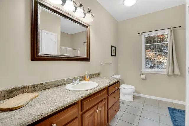 a bathroom with a granite countertop sink a toilet and mirror