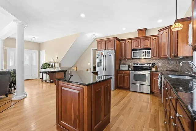 a kitchen with stainless steel appliances granite countertop a refrigerator a stove and a wooden floors