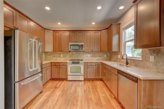 a kitchen with a refrigerator a sink and wooden cabinets