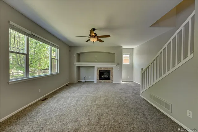 wooden floor in an empty room with a fireplace and a window