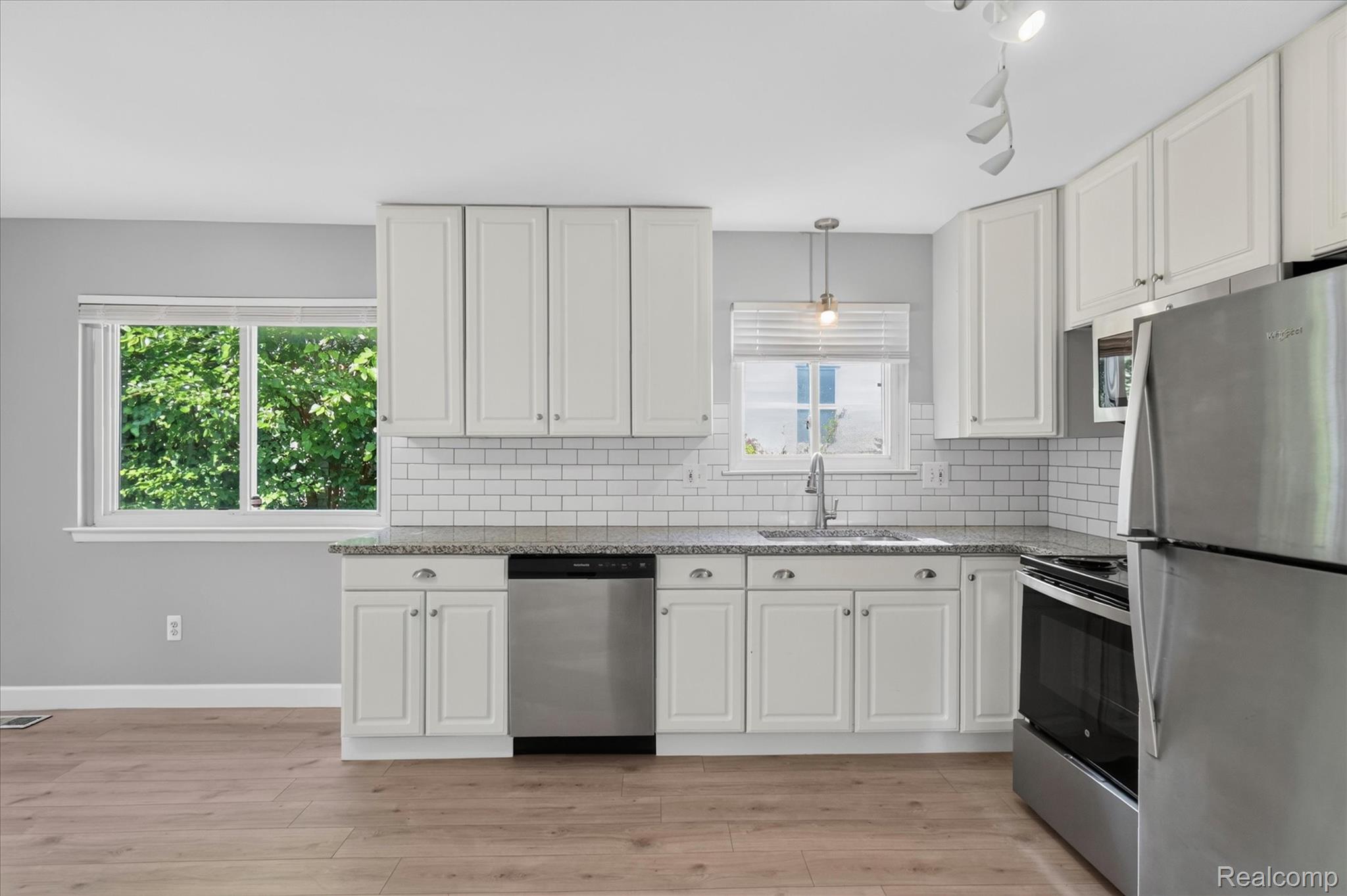 934 Harvard Road Berkley, MI 48072 - Photo 11 of 34 Kitchen featuring white shaker-style cabinetry, granite countertops, subway tile backsplash, stainless steel appliances, and wood-finish flooring