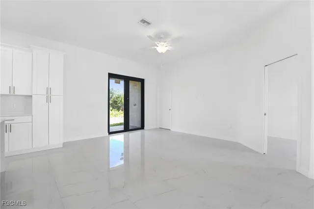 a view of an empty room with chandelier fan