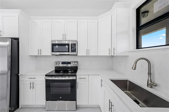 a kitchen with white cabinets stainless steel appliances and sink