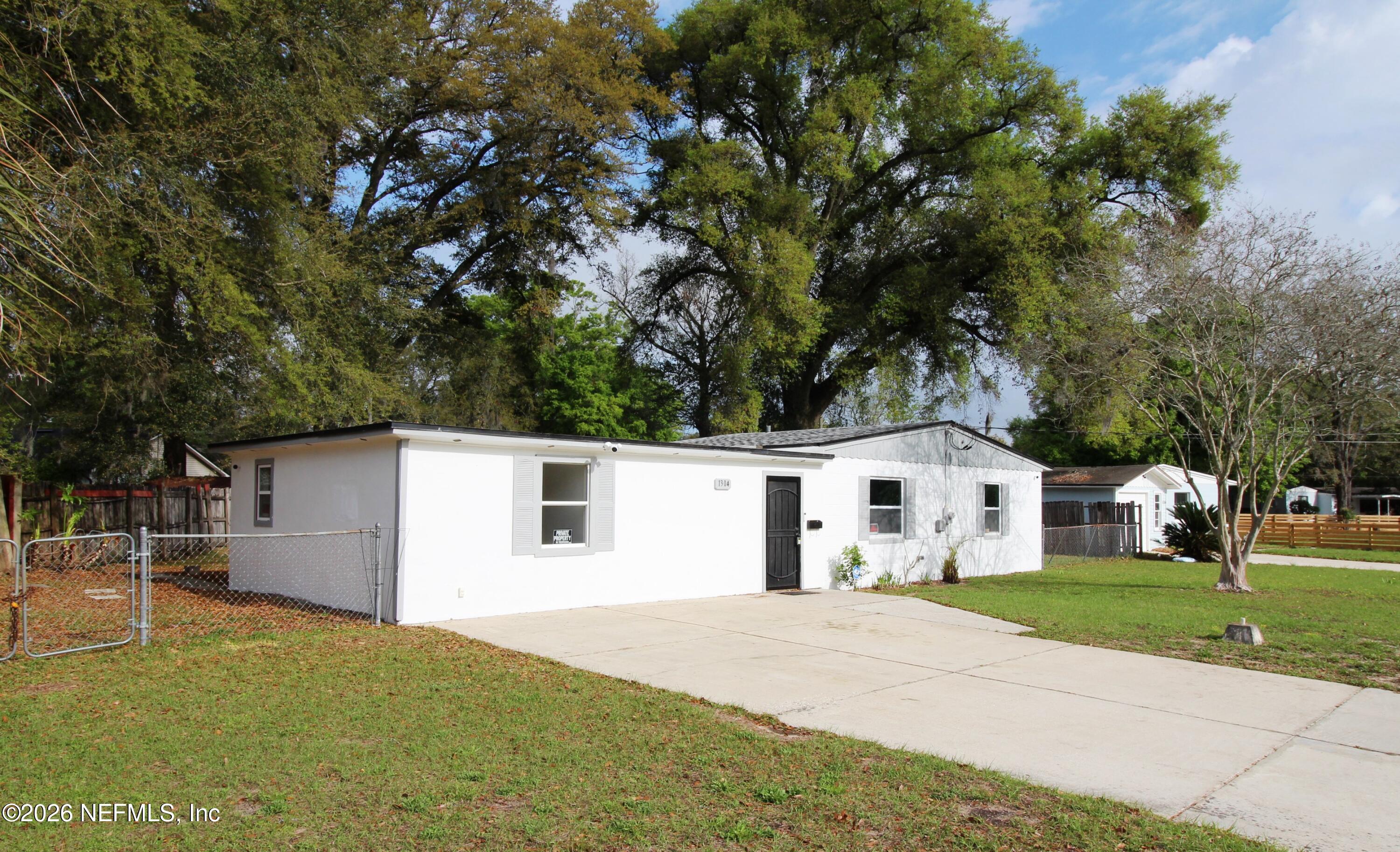 1304 King Arthur Road Jacksonville, FL 32211 - Photo 2 of 25 a white house with a big yard plants and large trees