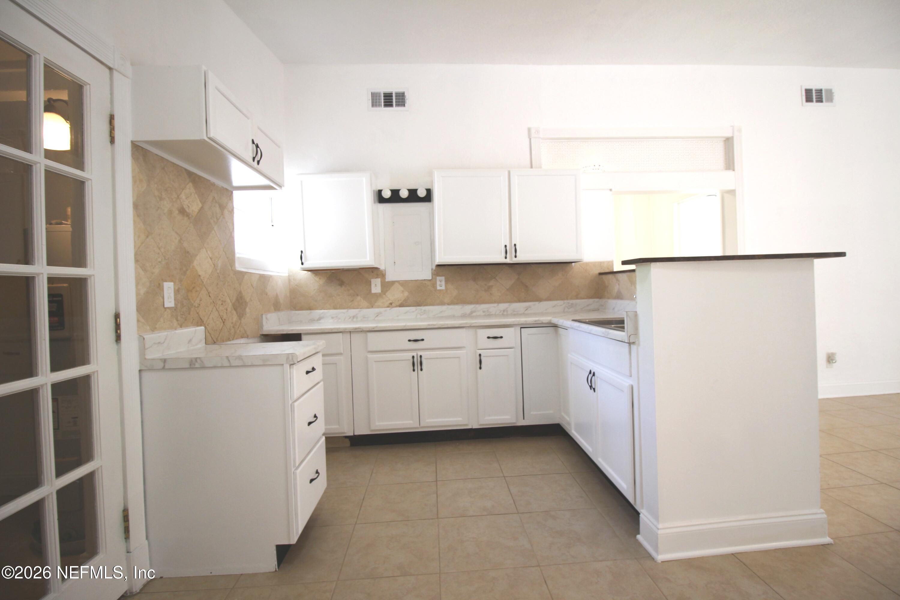 1304 King Arthur Road Jacksonville, FL 32211 - Photo 10 of 25 a kitchen with white cabinets and white appliances