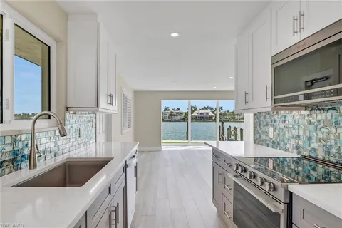 a kitchen with stainless steel appliances granite countertop a sink a stove and a wooden floors
