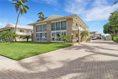 a front view of a building with a garden and palm trees