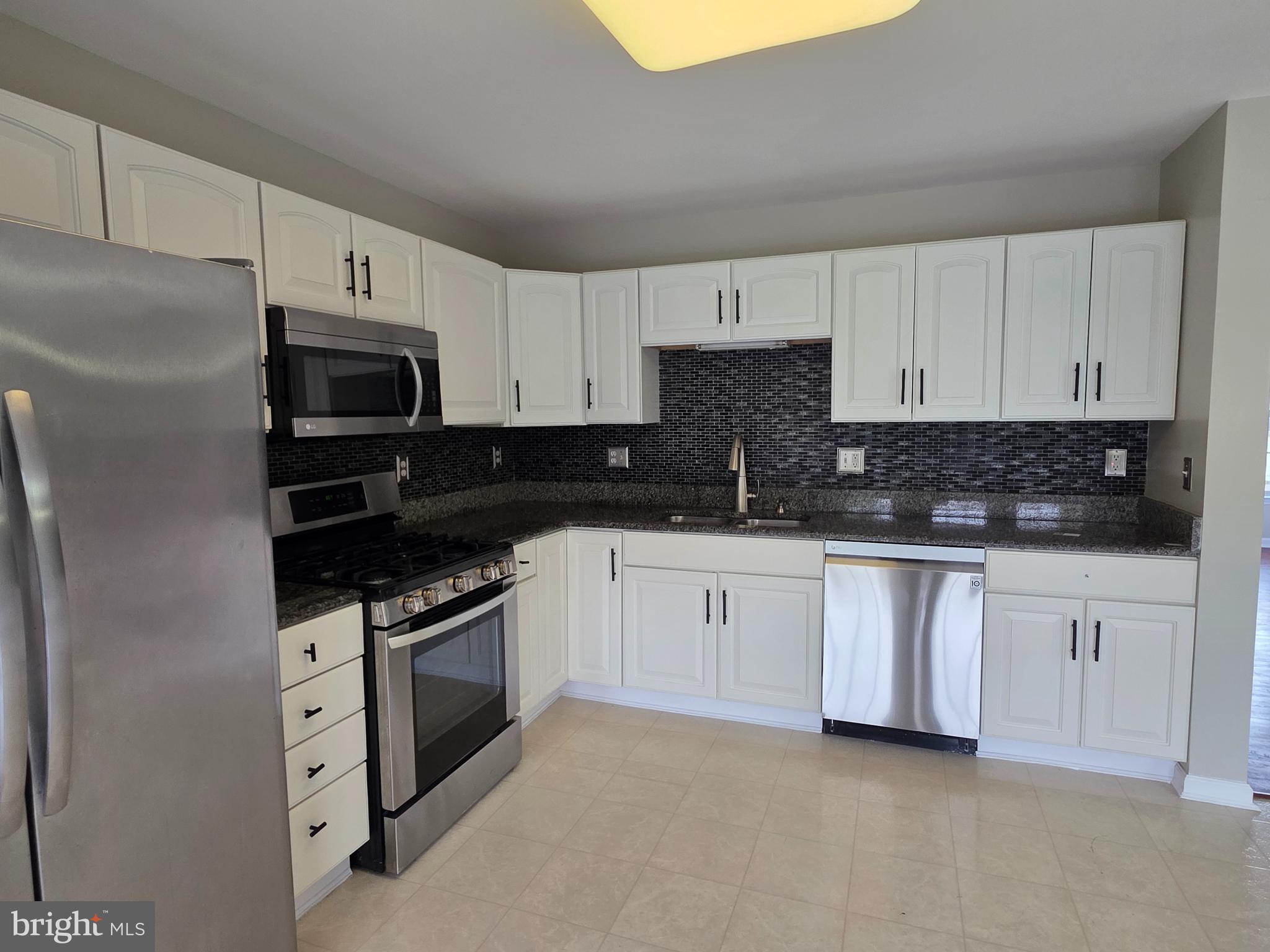 1002 Carlisle Road Egg Harbor Township, NJ 08234 - Photo 25 of 32 a kitchen with white cabinets and stainless steel appliances