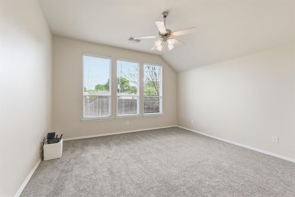 817 Huebner Way Burleson, TX 76028 - Photo 27 of 35 The primary bedroom has new carpet, vaulted ceiling, ceiling fan and three nice windows.