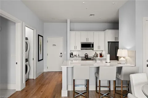 a kitchen with stainless steel appliances a stove a sink refrigerator and white cabinets with wooden floor