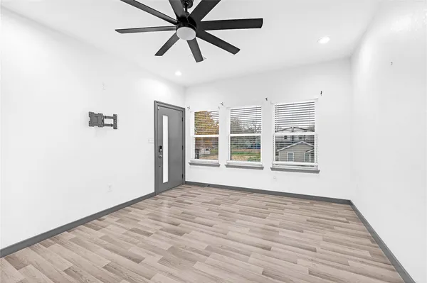 an empty room with wooden floor closet and windows