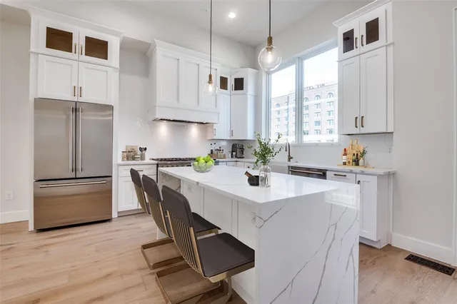 a kitchen with a refrigerator a stove a sink and white cabinets with wooden floor