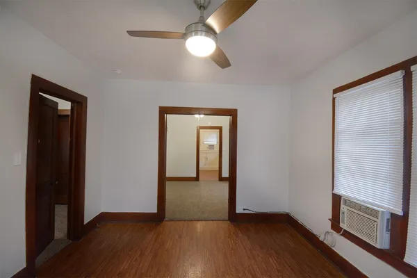 a view of an empty room with wooden floor and a window