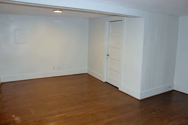 a view of an empty room with wooden floor and closet