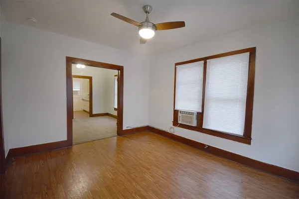 a view of an empty room with wooden floor and a window