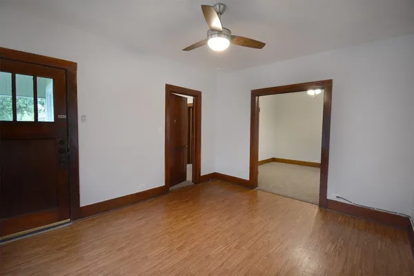 a view of an empty room with wooden floor and a window