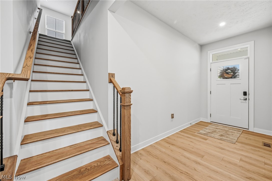 5358 Walnut Rdg Lane Sheffield Lake, OH 44054 - Photo 6 of 50 Foyer featuring a light wood-finish flooring, a white paneled entry door with transom window, and a staircase with wood treads and a wrought iron baluster