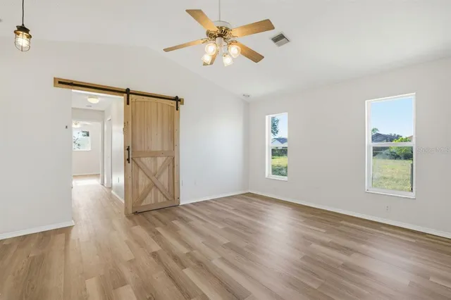 a view of an empty room with window and wooden floor