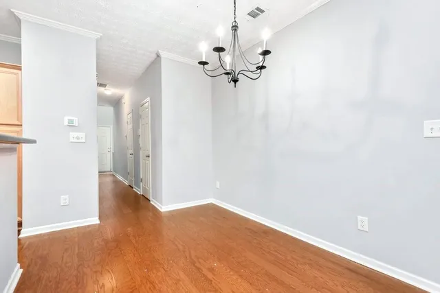 a view of a hallway with wooden floor and chandelier fan